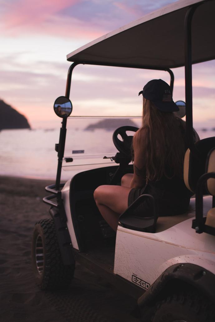 woman in black tank top riding on white and black golf cart during daytime